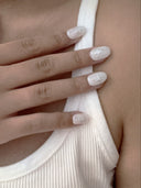 Close-up of a hand with light nail polish and a sea star pattern on a white sleeve