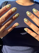 Nails with kiwi pattern against a blue shirt background